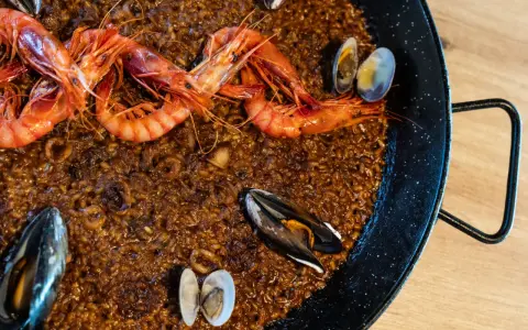 Paella de marisco recién hecha, con gambas rojas, mejillones y almejas sobre arroz dorado.